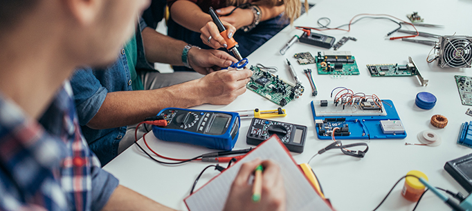 Group of students engineers working on a computer part