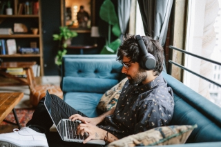 photo - Man Sitting on Couch at Home Working on Laptop
