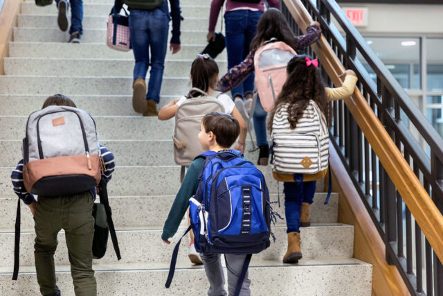 photo - students with backpacks climb staircase at school