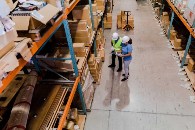 photo - Two Workers Using a Digital Tablet and a Clipboard To Double Check the Inventory in the Warehouse