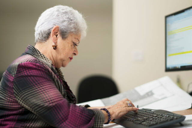 photo - Mature Woman Working on Spreadsheet in Office